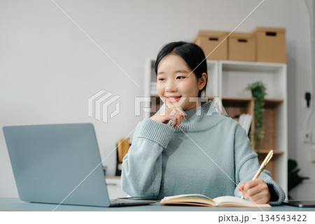 Confident Asian woman with a smile standing holding notepad and tablet at the office. 134543422