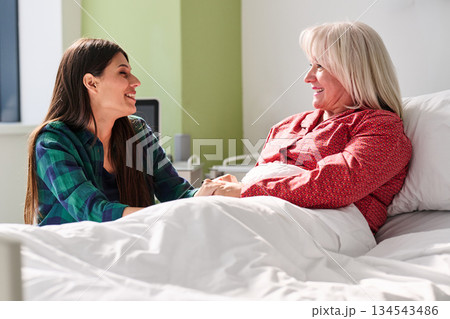 Family member visiting a loved one in the hospital, sharing smiles and support during recovery Family member visiting a loved one in the hospital, sharing smiles and support during recovery 134543486