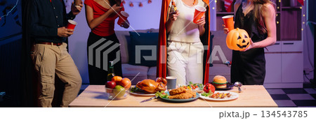 Halloween party with friends in costumes, enjoying drinks, food, and festive decorations. Perfect for autumn gatherings Halloween party with friends in costumes, enjoying drinks, food, and festive decorations. Perfect for autumn gatherings 134543785
