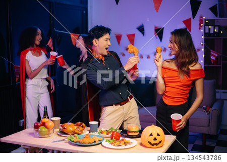 Halloween party with friends in costumes, enjoying drinks, food, and festive decorations. Perfect for autumn gatherings Halloween party with friends in costumes, enjoying drinks, food, and festive decorations. Perfect for autumn gatherings 134543786