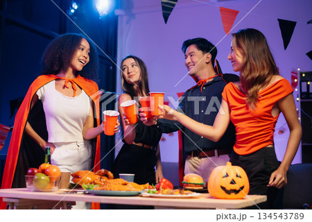 Halloween party with friends in costumes, enjoying drinks, food, and festive decorations. Perfect for autumn gatherings Halloween party with friends in costumes, enjoying drinks, food, and festive decorations. Perfect for autumn gatherings 134543789