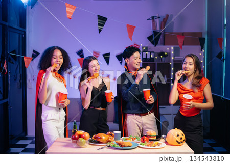 Halloween party with friends in costumes, enjoying drinks, food, and festive decorations. Perfect for autumn gatherings 134543810