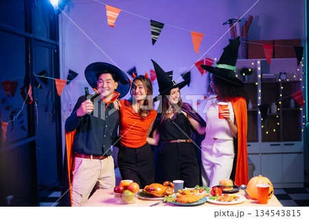 Halloween party with friends in costumes, enjoying drinks, food, and festive decorations. Perfect for autumn gatherings Halloween party with friends in costumes, enjoying drinks, food, and festive decorations. Perfect for autumn gatherings 134543815