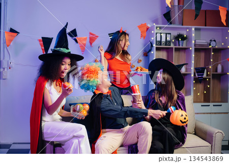 Halloween party with friends in costumes, enjoying drinks, food, and festive decorations. Perfect for autumn gatherings Halloween party with friends in costumes, enjoying drinks, food, and festive decorations. Perfect for autumn gatherings 134543869