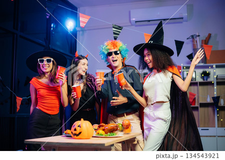 Halloween party with friends in costumes, enjoying drinks, food, and festive decorations. Perfect for autumn gatherings 134543921