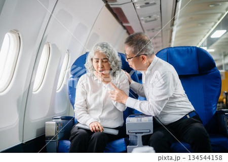 Senior Asian couple capturing memories on a plane, blending travel with technology. Smiling, stylish, Senior Asian couple capturing memories on a plane, blending travel with technology. Smiling, stylish, 134544158