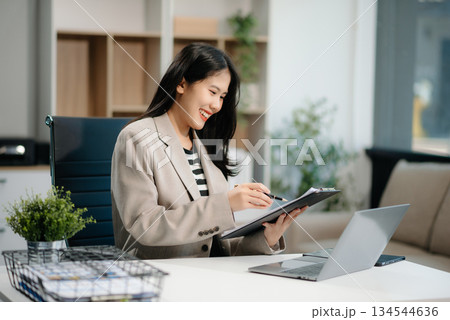 Beautiful Asian businesswoman typing laptop and tablet Placed at the table at the office 134544636