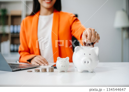 Women are putting coins in a piggy bank for a business that grows for profit and saving money for the future. planning 134544647
