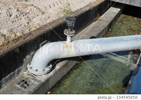 都市化が進む農地の水利インフラ：悪臭漂う下水路に設置された農業用水パイプと給水栓 134545050