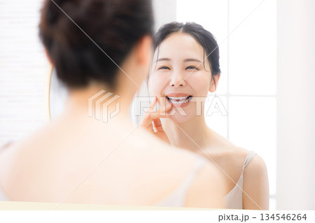鏡の前でスキンケアを確認する女性　口元ケア(ホワイトニングや歯並び）と美肌 134546264