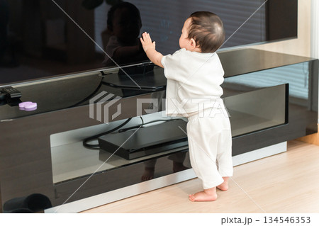 家のリビングでつかまり立ちをする赤ちゃん（歩く,発育,成長,発達） 134546353