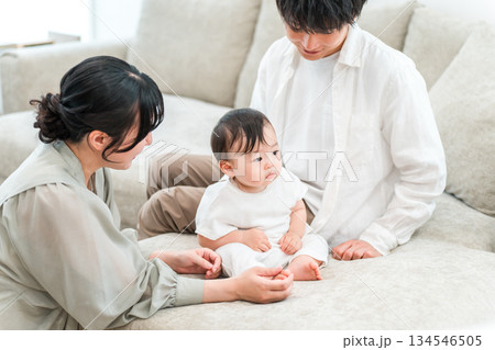 マイホームのリビングソファーで赤ちゃんと過ごす若いファミリー,家族 マイホームのリビングソファーで赤ちゃんと過ごす若いファミリー,家族 134546505