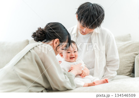 マイホームのリビングソファーで赤ちゃんと過ごす若いファミリー,家族 134546509