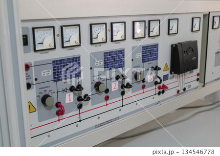Technical detail shot of a didactic PV system trainer board displaying controls for solar irradiance simulation and measurement gauges for voltage and current parameters. Technical detail shot of a didactic PV system trainer board displaying controls for solar irradiance simulation and measurement gauges for voltage and current parameters. 134546778