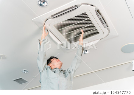 エアコン・空調設備の清掃,点検をする作業着の男性 134547770