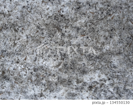 A dirty snowy surface with soil and natural particles, snow-covered asphalt. Textured background, top view. Winter season concept for design. A dirty snowy surface with soil and natural particles, snow-covered asphalt. Textured background, top view. Winter season concept for design. 134550130