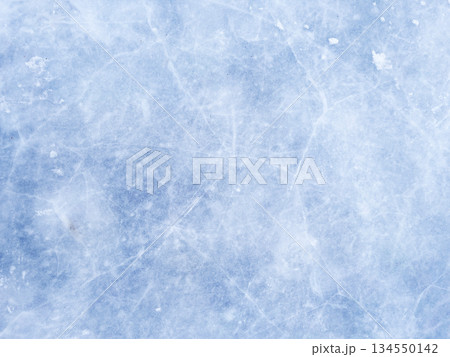 A background of blue ice with scratches and cracks. The frozen surface of a lake, a Christmas winter skating rink. A textured backdrop for New Year's, winter sports, and entertainment. 134550142