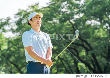 ゴルフ場でゴルフをするゴルファーの男性(真剣・ティーショット・ゴルフコンペ) ゴルフ場でゴルフをするゴルファーの男性(真剣・ティーショット・ゴルフコンペ) 134550726