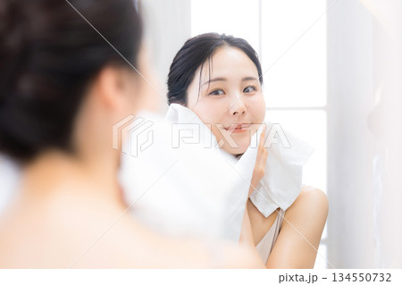 洗顔後に鏡を見るオルでケアする女性　保湿とスキンケア 134550732