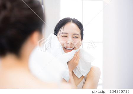 洗顔後に鏡を見るオルでケアする女性　保湿とスキンケア 134550733