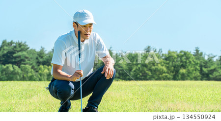 ゴルフ場のグリーン上でラインを読む男性ゴルファー 134550924