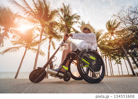 Disabled man in a wheelchair with electric scooter on the beach Disabled man in a wheelchair with electric scooter on the beach 134551608