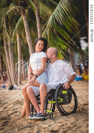 Disabled man in a wheelchair with his wife on the beach. 134551618