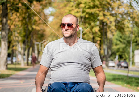 Handicapped man in wheelchair walk at the park alley Handicapped man in wheelchair walk at the park alley 134551658