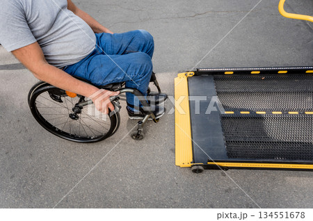 A man in a wheelchair moves to the lift of a specialized vehicle A man in a wheelchair moves to the lift of a specialized vehicle 134551678
