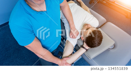 Rehabilitation therapy. Physiotherapist working with young male patient Rehabilitation therapy. Physiotherapist working with young male patient 134551839