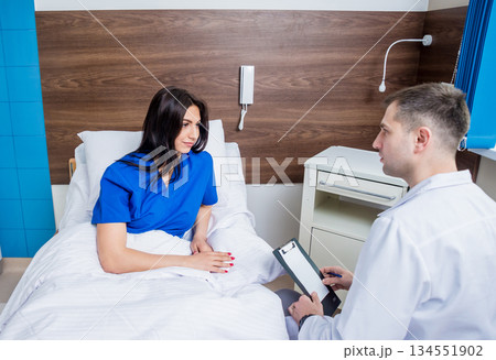 Traumatologist talking with young female patient in modern hospital Traumatologist talking with young female patient in modern hospital 134551902