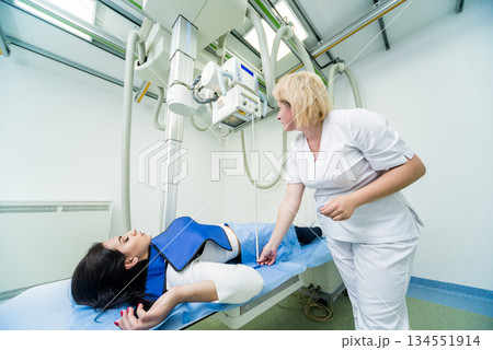 Radiologist and patient in a x-ray room. Classic ceiling-mounted x-ray system. Radiologist and patient in a x-ray room. Classic ceiling-mounted x-ray system. 134551914