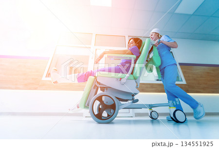 Nurse moves mobile medical chair with patient at hospital. Medical equipment. 134551925
