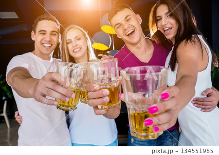 Cheerful friends in the pub. Drinking beer, talking, having fun. 134551985