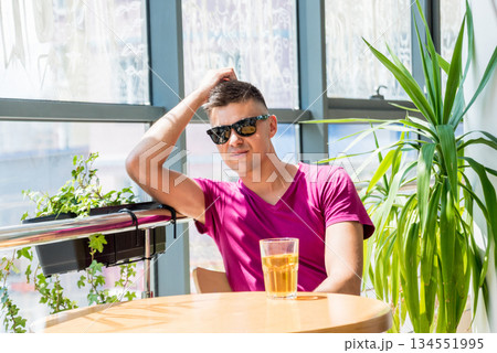 Young man in the pub. Drinking beer, eating pizza. 134551995