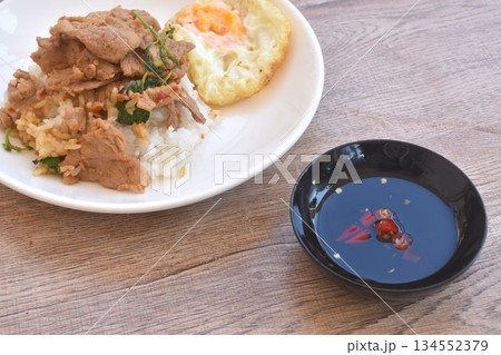 spicy fried slice fermenting soft pork with basil topping egg on rice in plate dipping chili fish sauce 134552379
