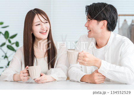 ダイニングテーブルでホットドリンクを飲みながら会話するカップル,夫婦 134552529