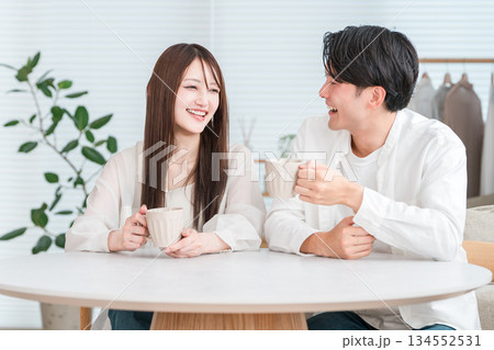 ダイニングテーブルでホットドリンクを飲みながら会話するカップル,夫婦 134552531