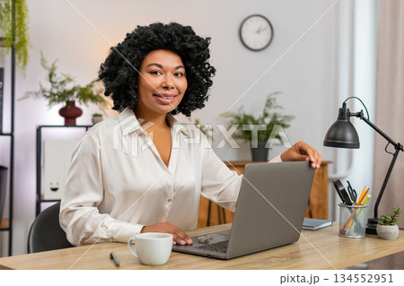 African American businesswoman happily opens laptop and types fast starting productive new workday 134552951