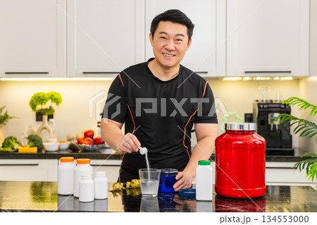 Sportsman pours supplement powder into glass of water in kitchen at home for daily fitness energy up Sportsman pours supplement powder into glass of water in kitchen at home for daily fitness energy up 134553000