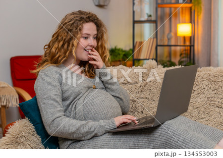 Pregnant woman browsing baby products on laptop, smiling with excitement emotional anticipation Pregnant woman browsing baby products on laptop, smiling with excitement emotional anticipation 134553003