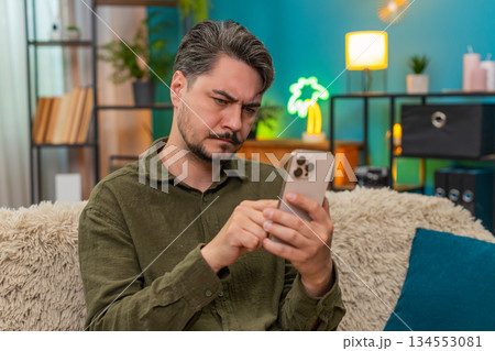 Middle-aged man slowly editing smartphone text deletes rewrites hesitates deciding what to message Middle-aged man slowly editing smartphone text deletes rewrites hesitates deciding what to message 134553081