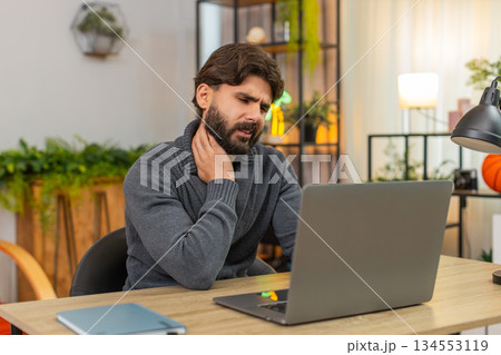 Indian man stops work due to neck pain massages neck unhappy face closes laptop for short break sore Indian man stops work due to neck pain massages neck unhappy face closes laptop for short break sore 134553119