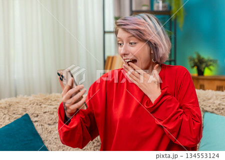 Young woman celebrating victory in online mobile game, expressing excited surprise joyful emotions Young woman celebrating victory in online mobile game, expressing excited surprise joyful emotions 134553124