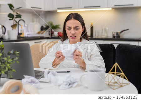 Young woman writes ideas at laptop creative block self critique crumpled paper demotivated tired Young woman writes ideas at laptop creative block self critique crumpled paper demotivated tired 134553125