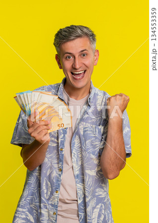 Adult man jumping with joy waving and holding euro cash celebrating win in lottery game or jackpot Adult man jumping with joy waving and holding euro cash celebrating win in lottery game or jackpot 134553359