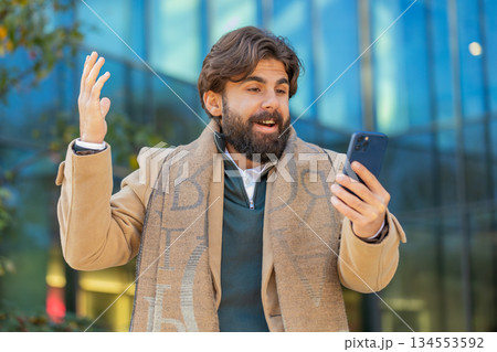 Happy Indian man using smartphone celebrating victory win good message news on downtown city street Happy Indian man using smartphone celebrating victory win good message news on downtown city street 134553592