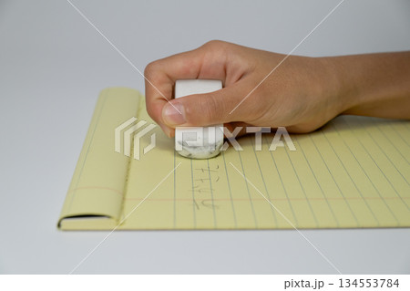 ノートの文字を消しゴムで消す手元のアップ 134553784