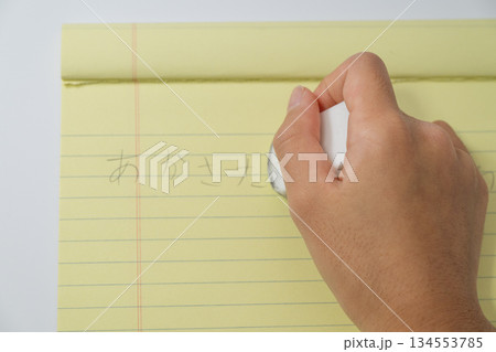 ノートの文字を消しゴムで消す手元の俯瞰 134553785