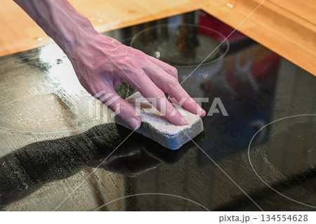 Hand cleaning ceramic cooktop with sponge in modern kitchen Hand cleaning ceramic cooktop with sponge in modern kitchen 134554628